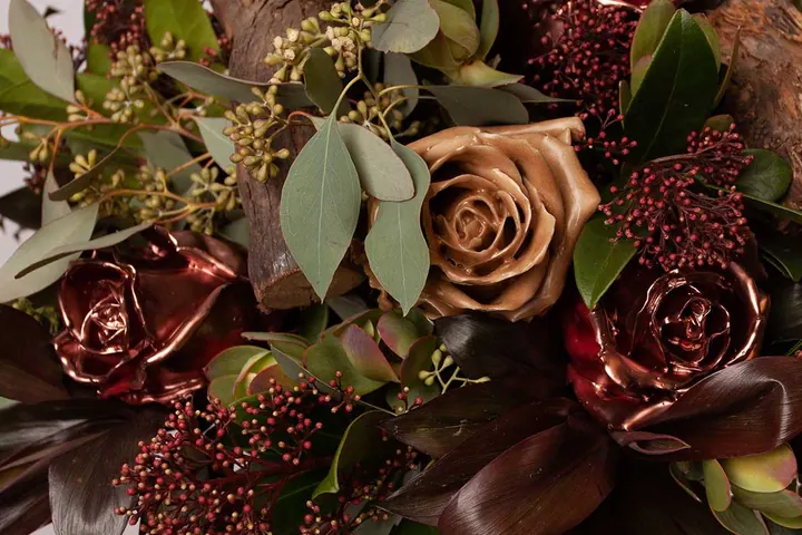 Stuk met koperen en bronzen waxrozen, skimmia en eucalyptus